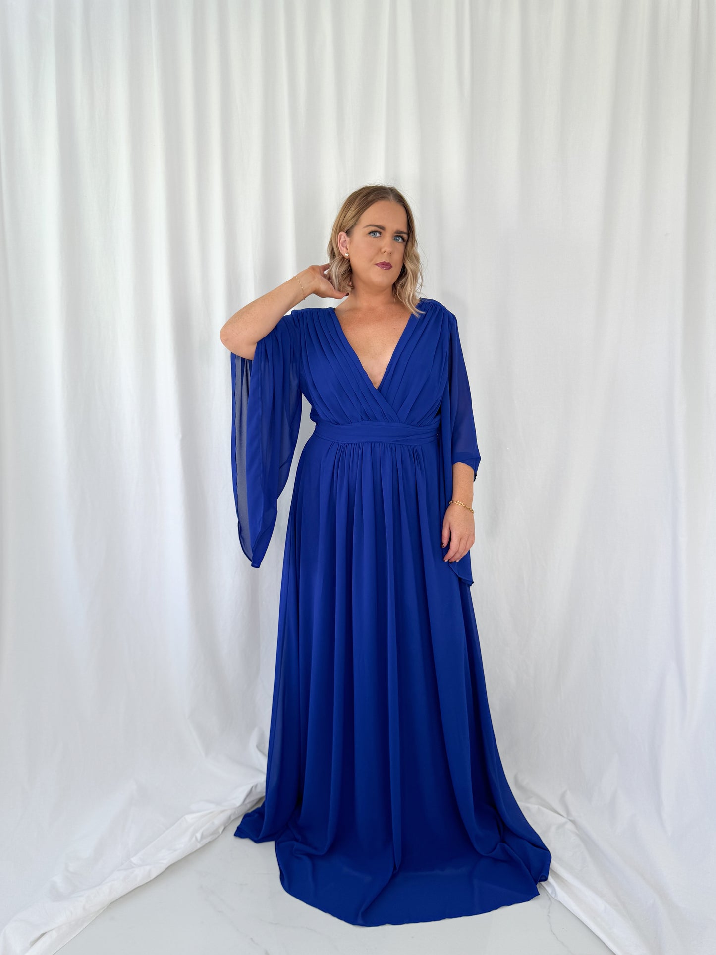 a woman in a blue dress talking on a cell phone