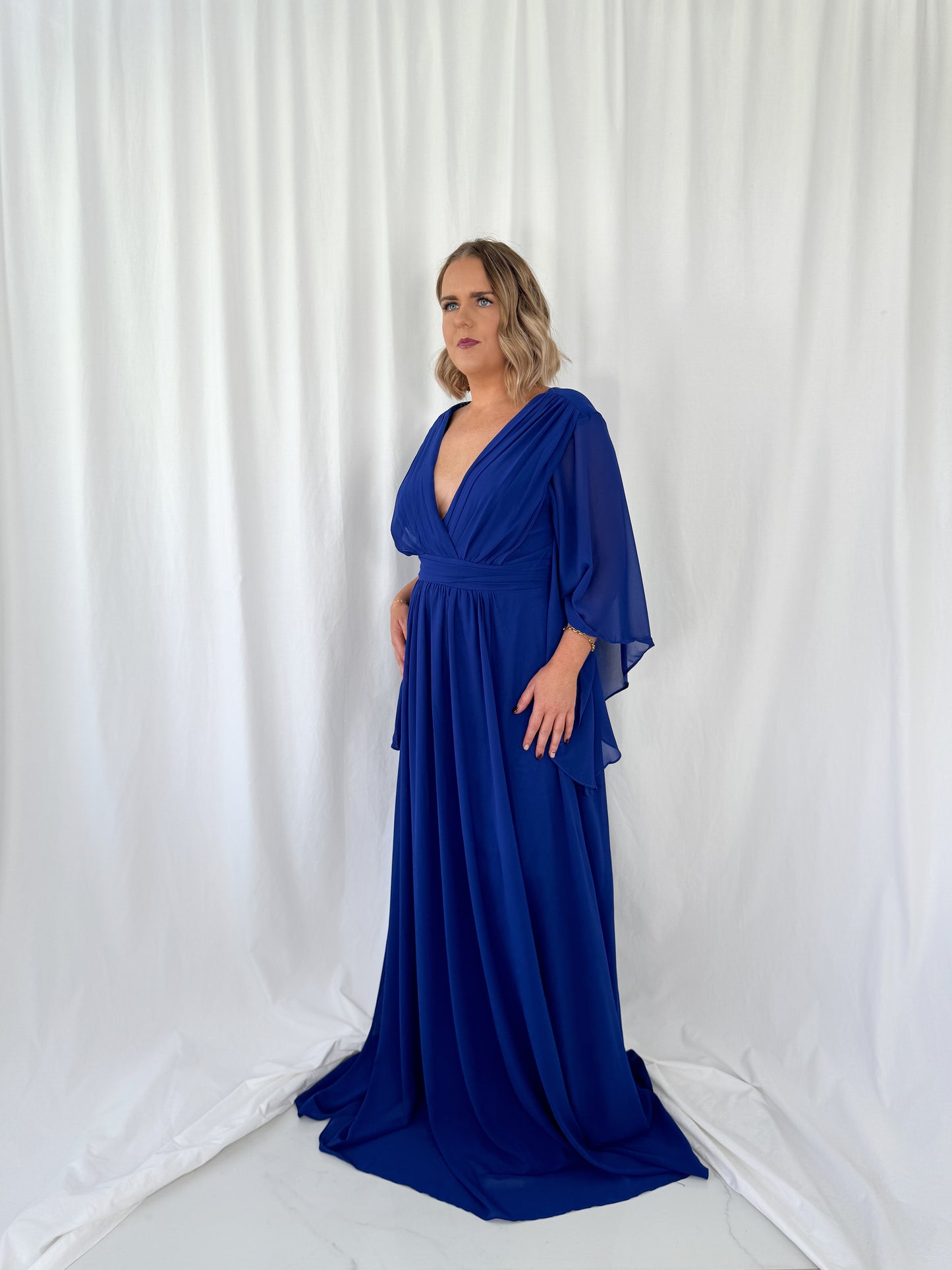 a woman in a blue dress standing in front of a curtain