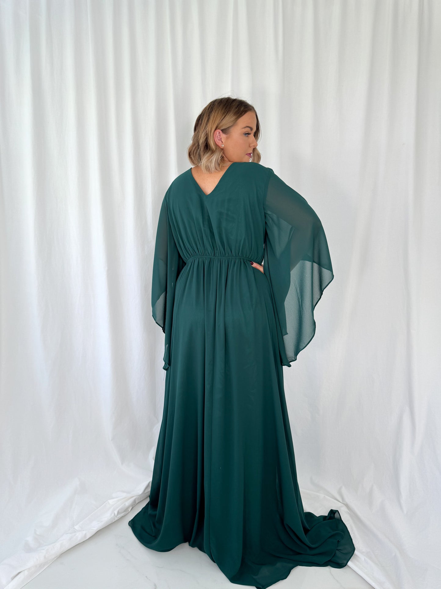 a woman in a green dress talking on a cell phone