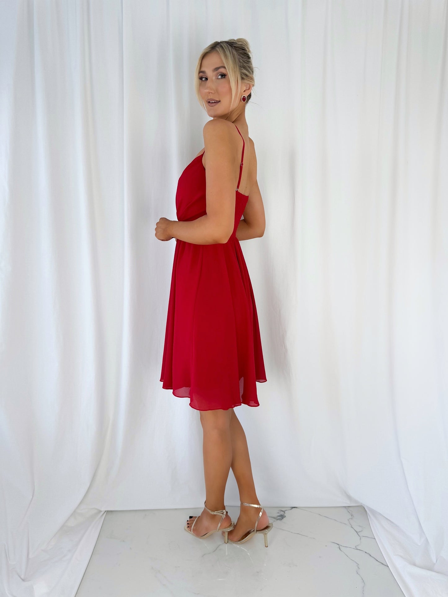 a woman in a red dress standing in front of a curtain