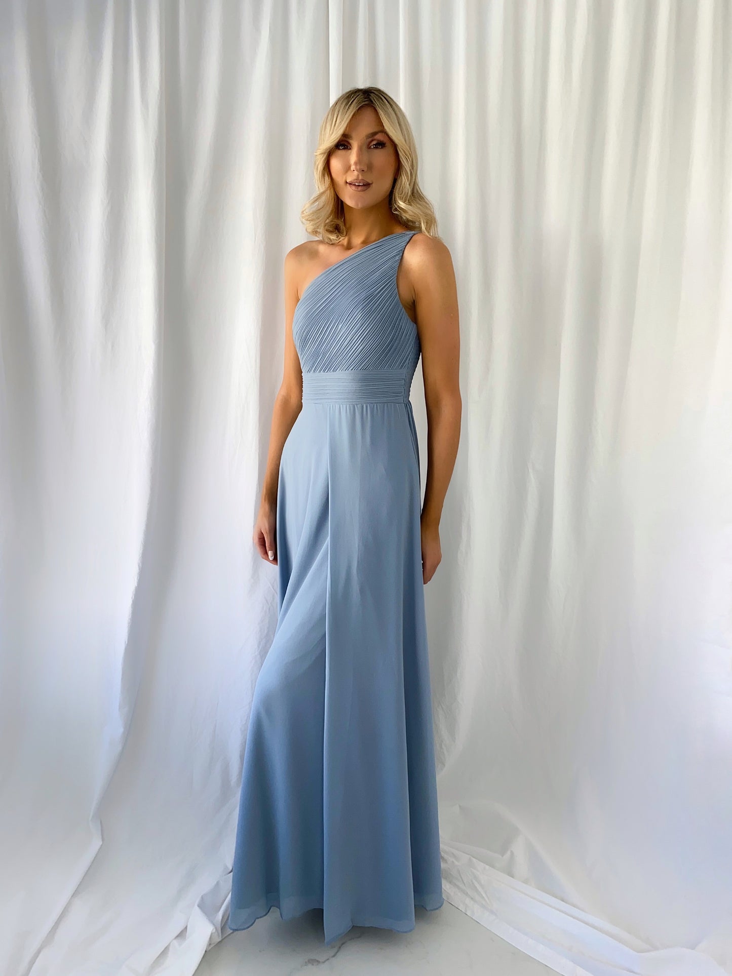 a woman standing next to a white wall