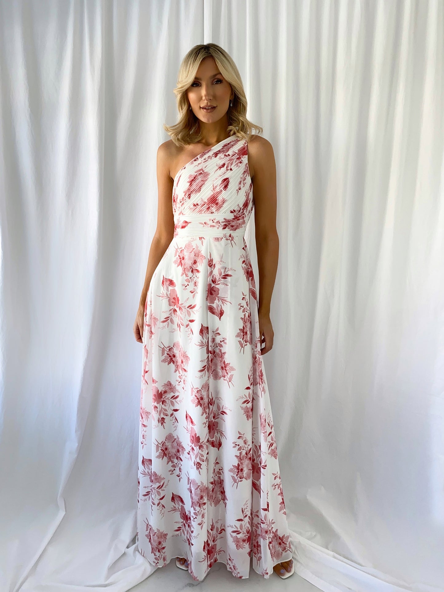 a woman in a pink dress standing in front of a curtain
