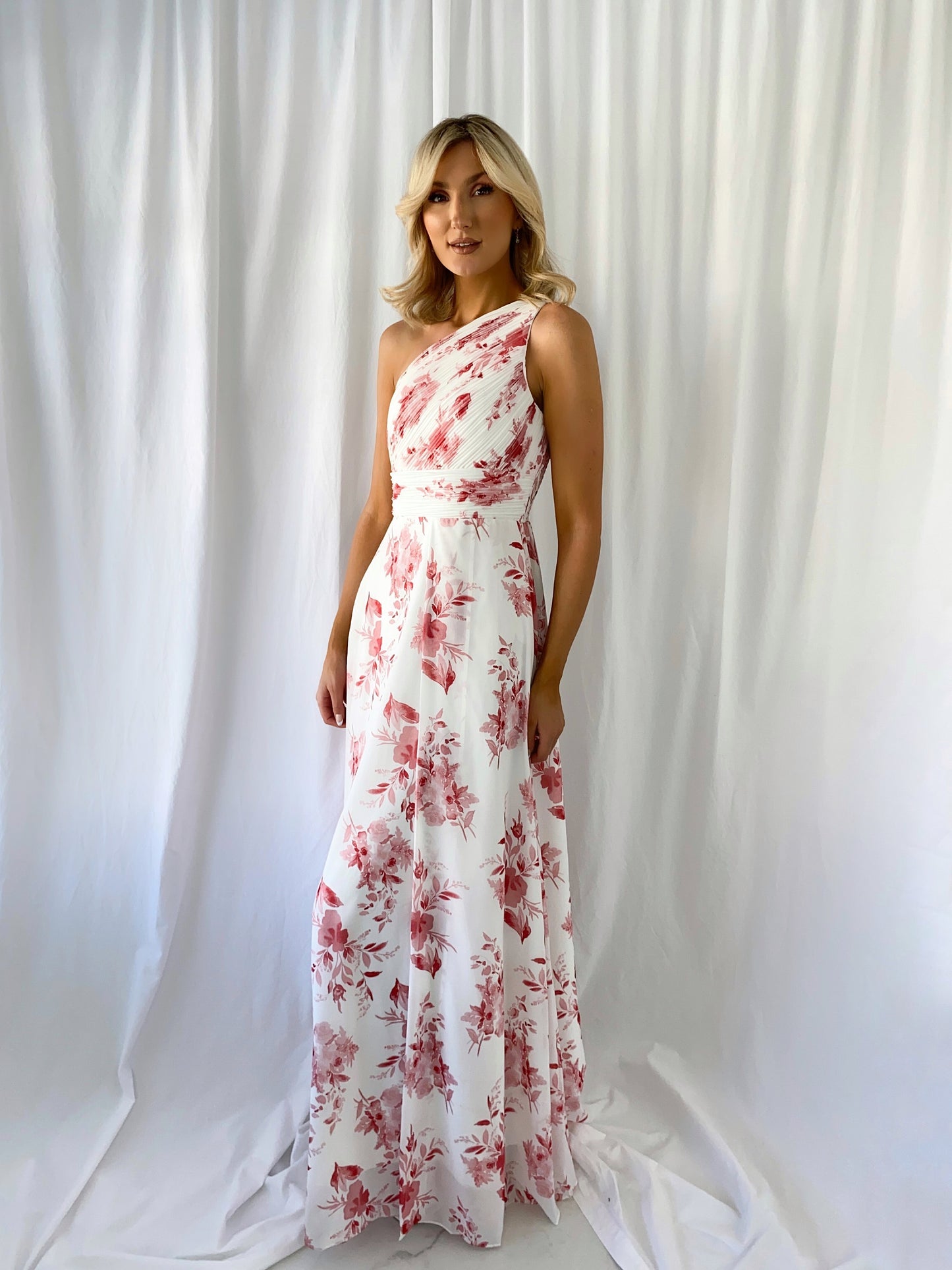 a woman in a pink dress standing in front of a curtain
