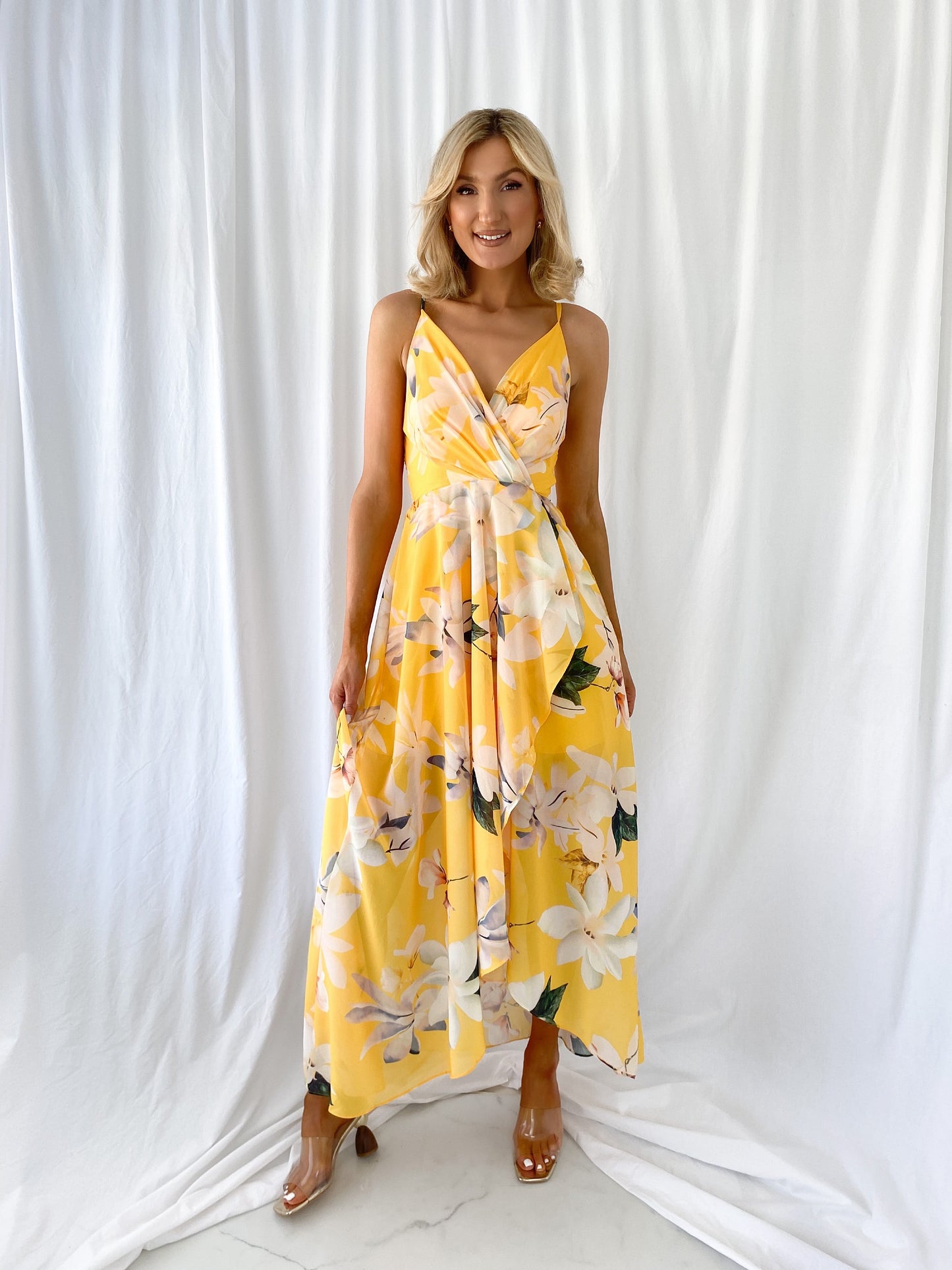 a woman in a yellow dress standing in front of a curtain