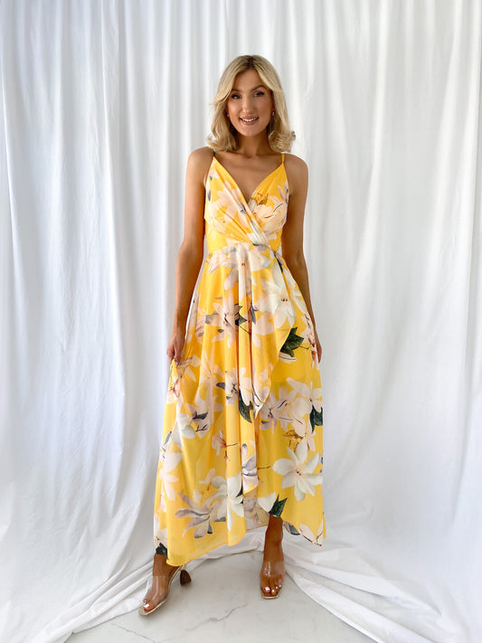 a woman in a yellow dress standing in front of a curtain 