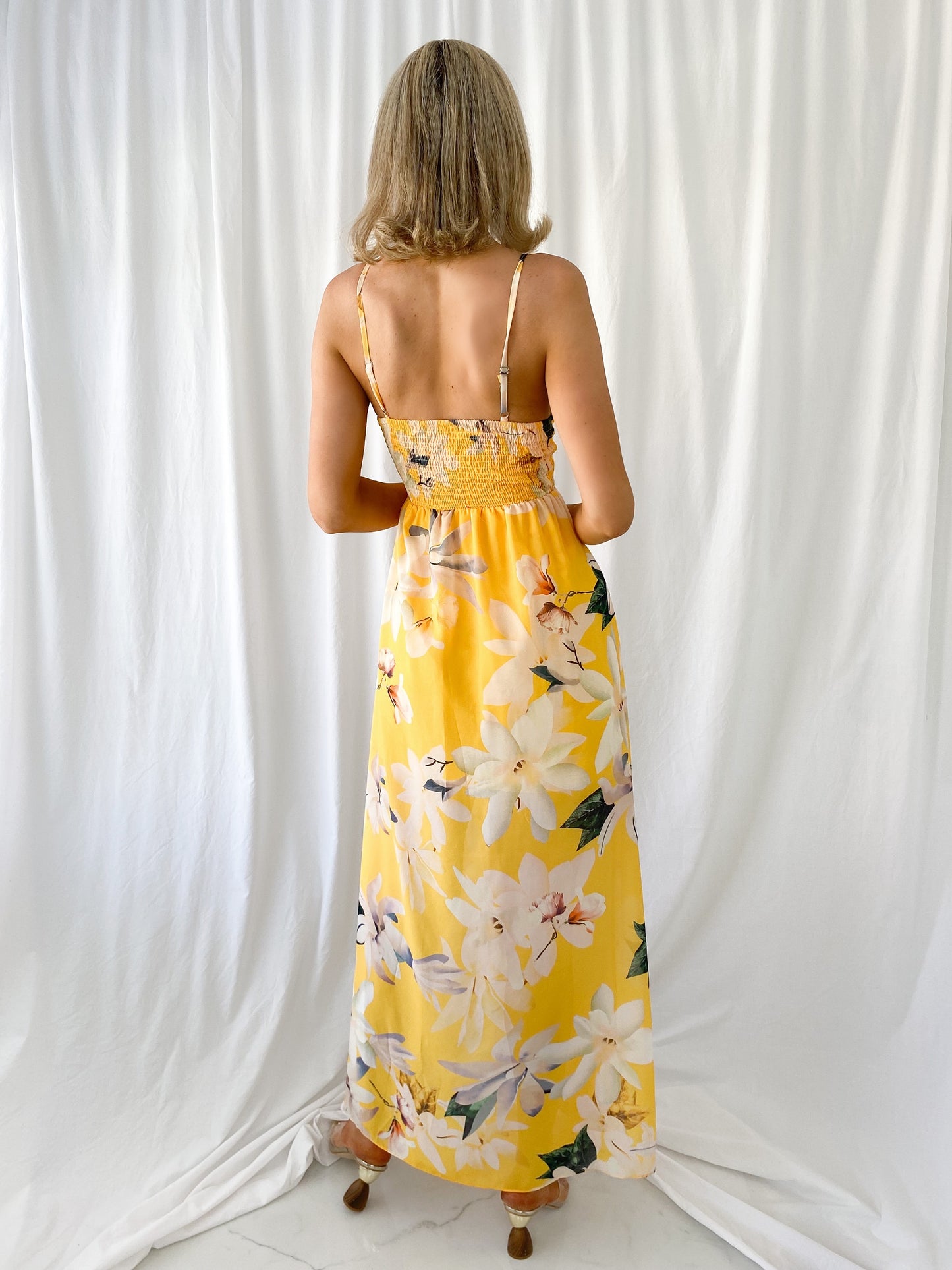 a woman in a yellow dress holding a yellow fire hydrant 