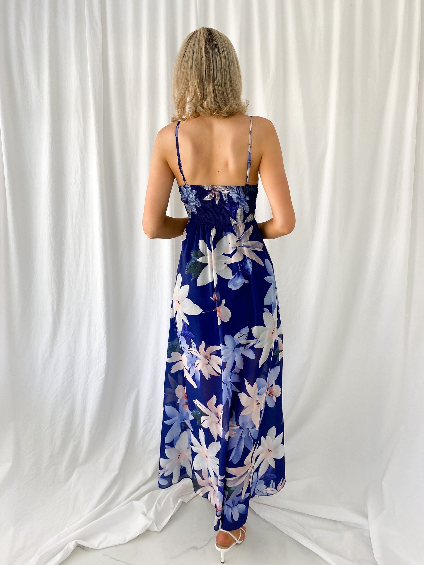 a woman in a blue dress holding a cell phone