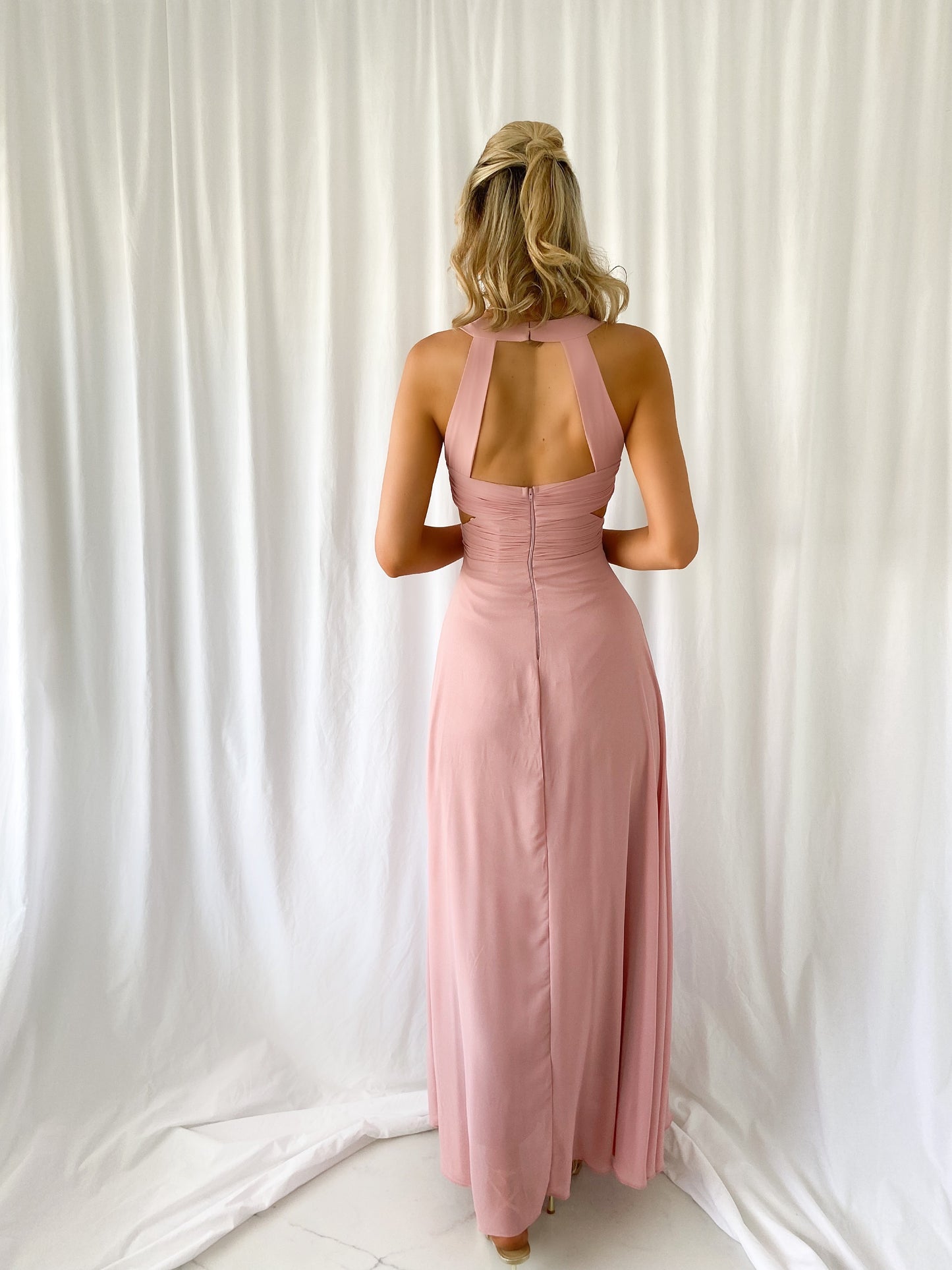 a woman in a pink dress standing on a bed