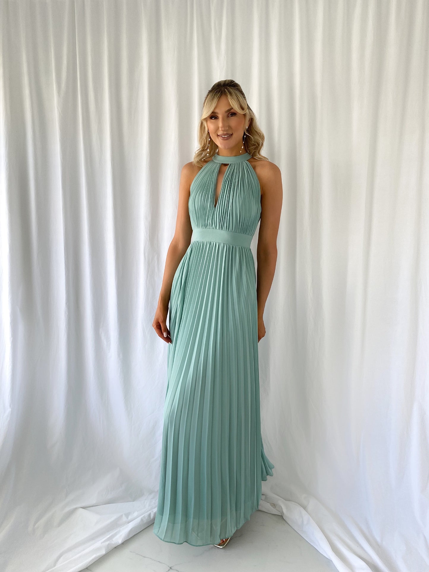 a woman in a green dress standing in front of a curtain