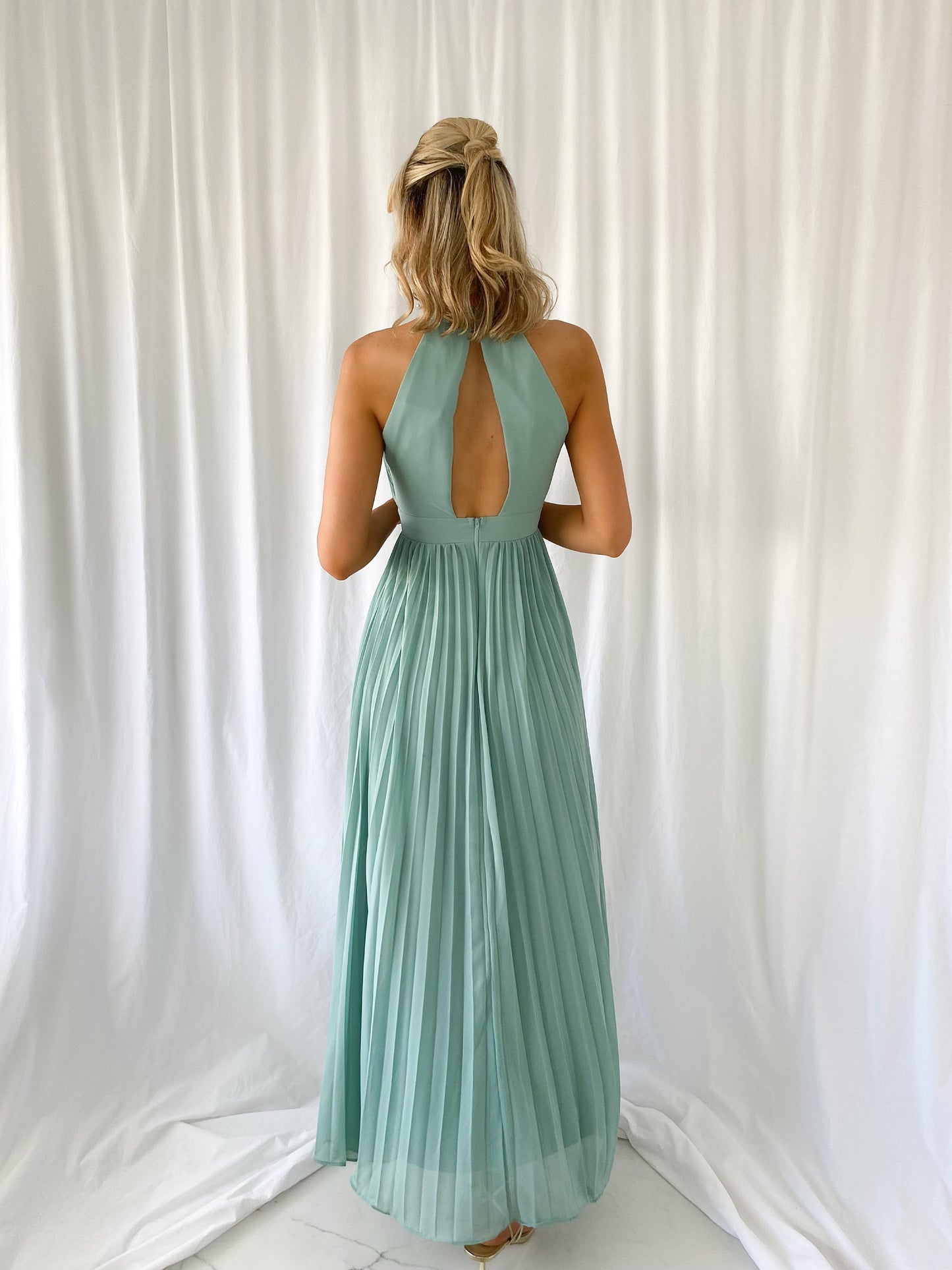a woman in a green dress talking on a cell phone