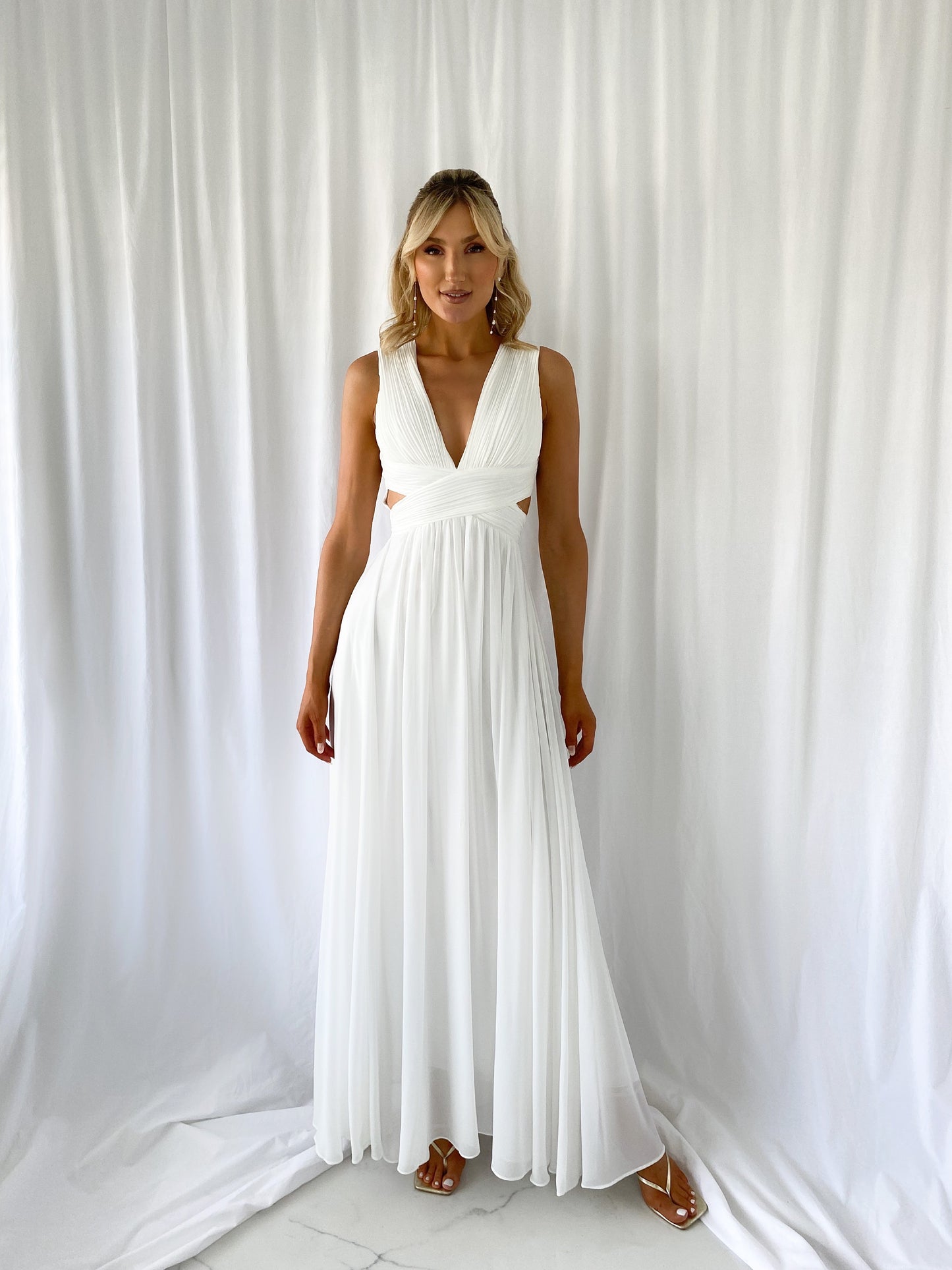 a woman in a white dress standing next to a white curtain 