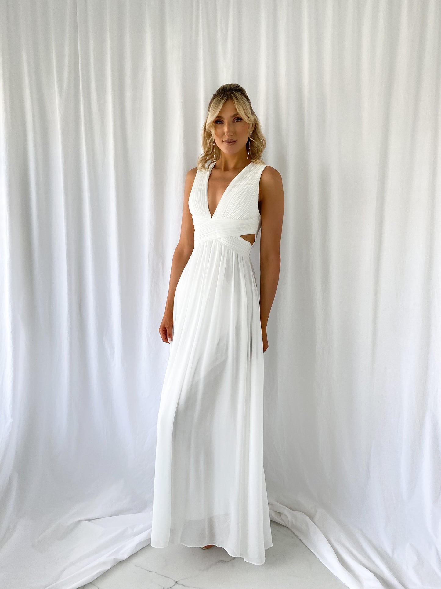 a woman in a white dress talking on a cell phone