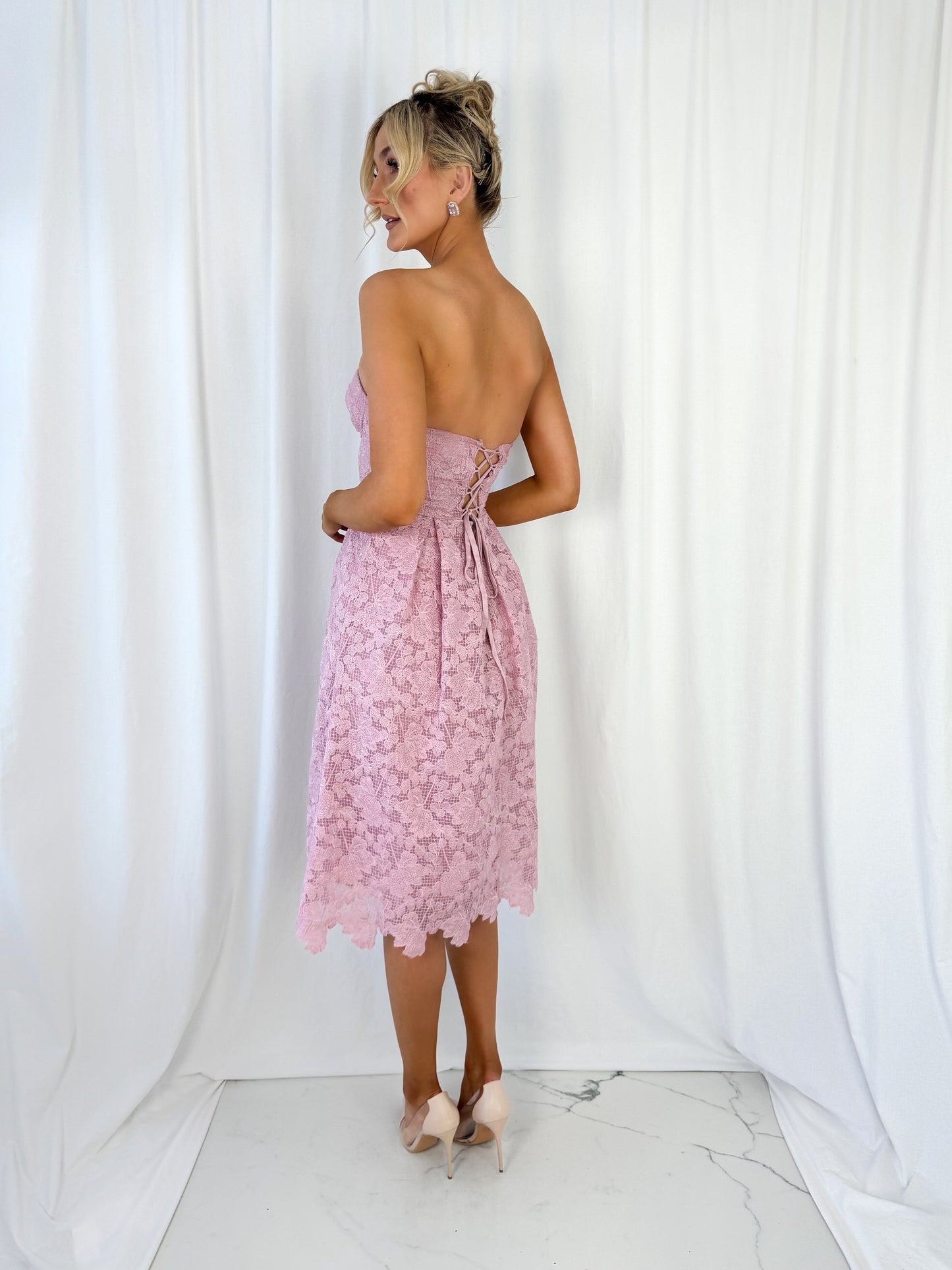 a woman in a pink dress standing in a white dress