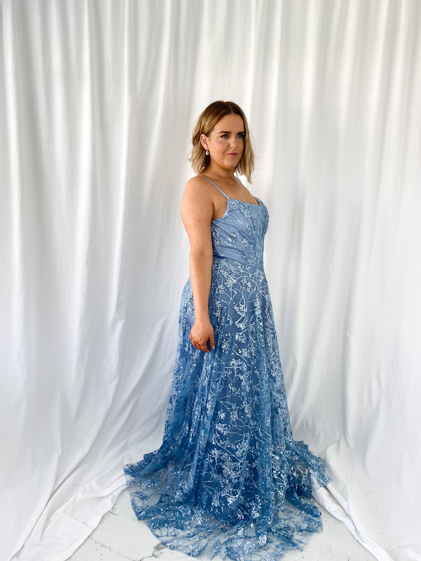 a woman in a white dress is talking on a cell phone