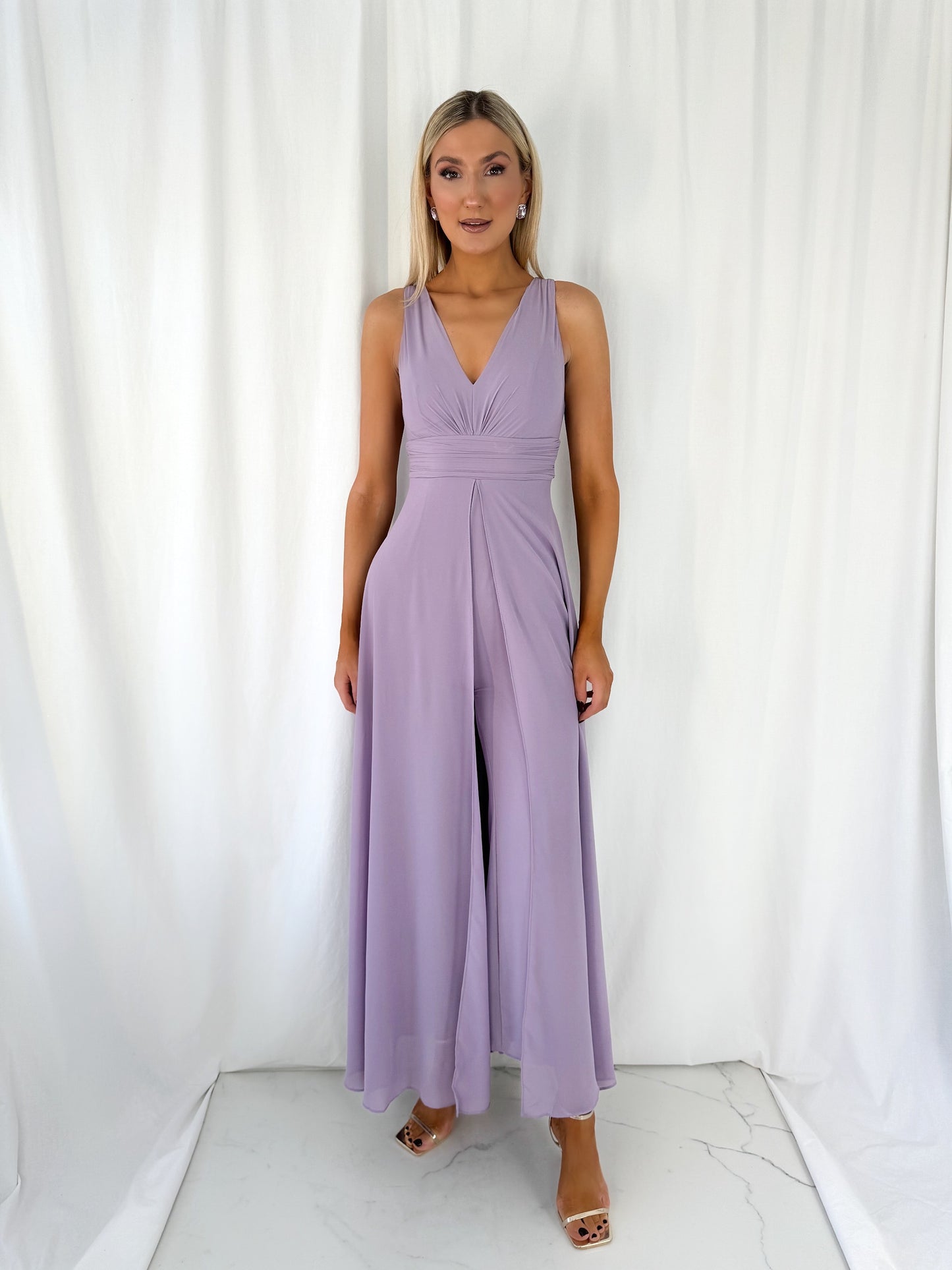 a woman in a pink dress standing in front of a curtain 