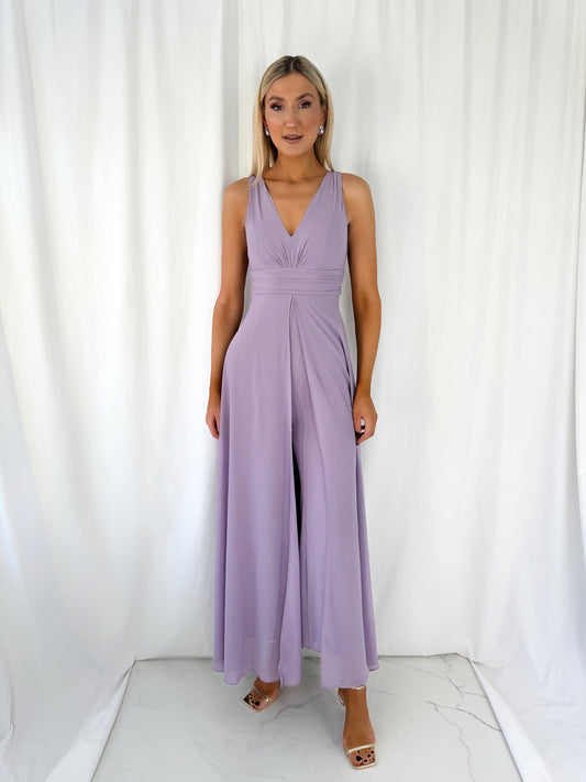 a woman in a pink dress standing in front of a curtain
