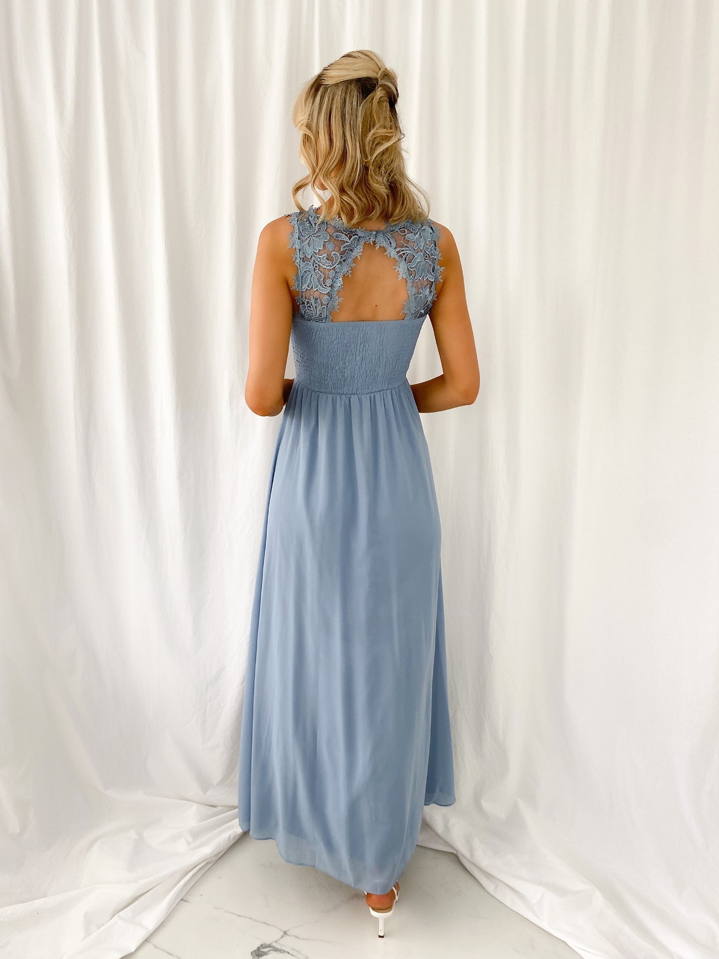 a woman in a blue dress is talking on a cell phone