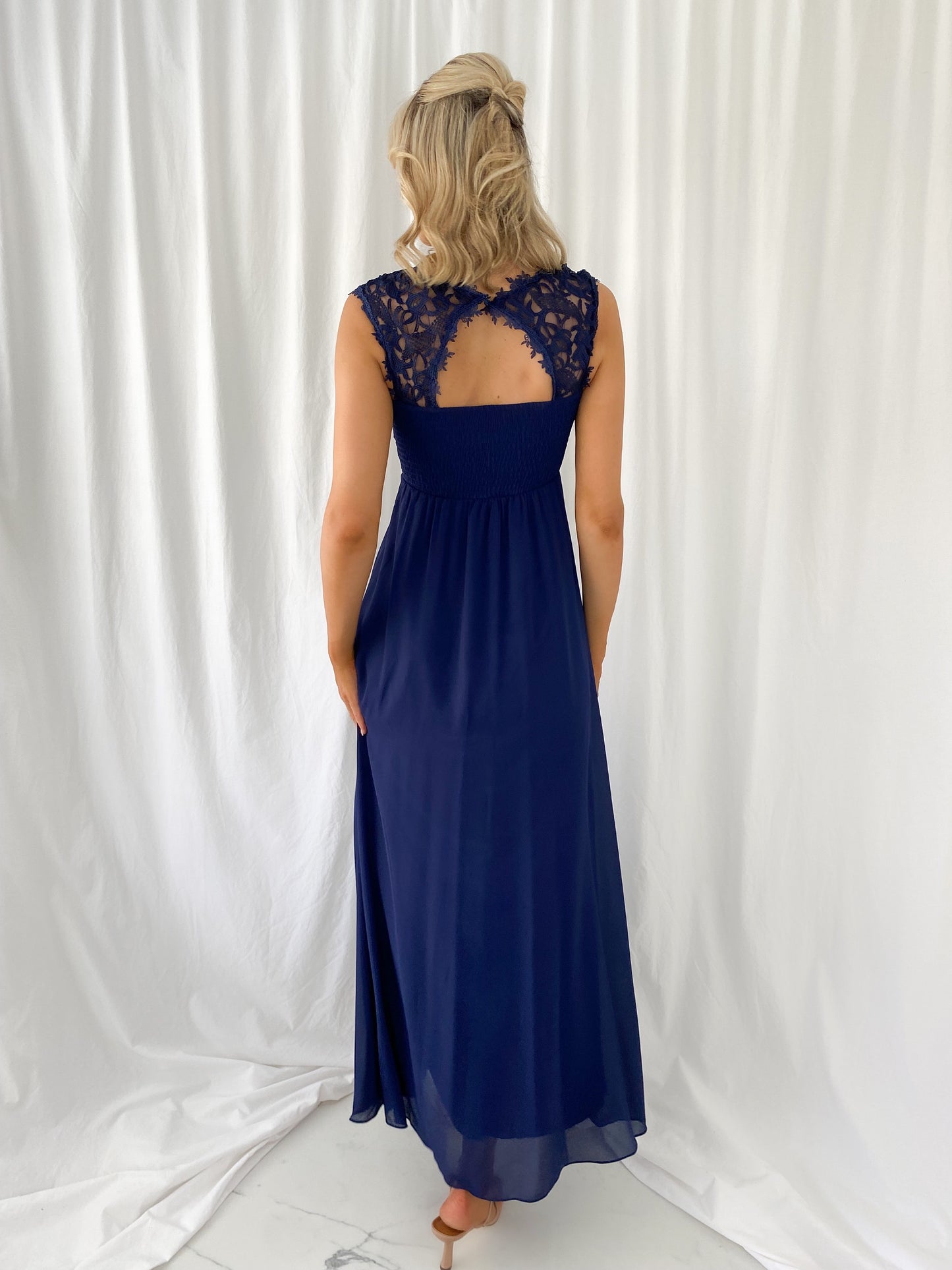 a woman in a blue dress standing in front of a curtain
