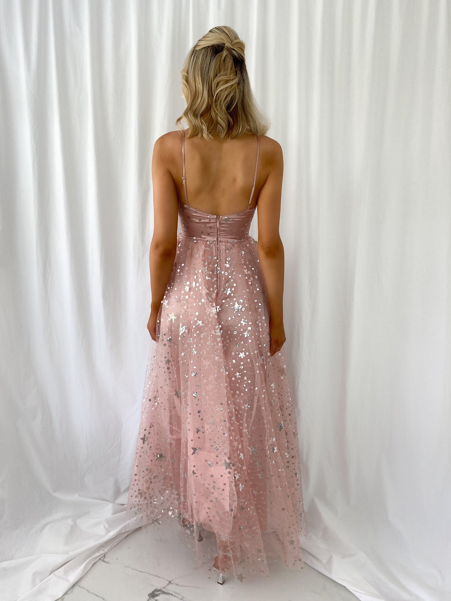 a woman in a bikini standing next to a pink fire hydrant