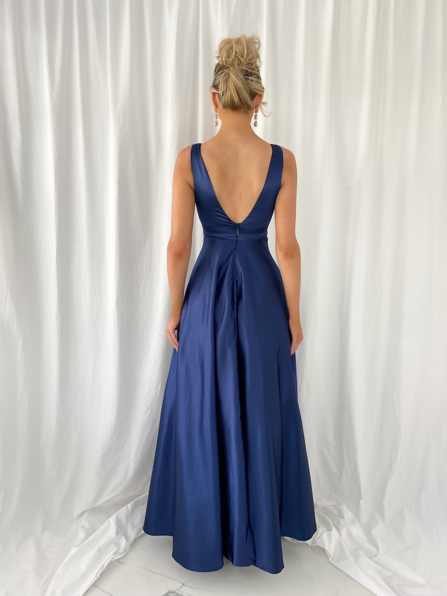 a woman in a blue dress is talking on a cell phone