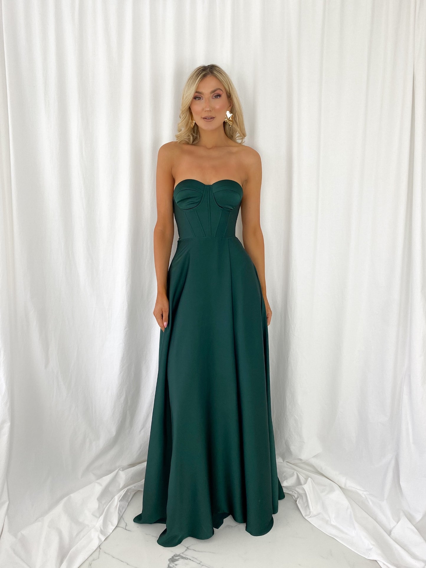 a woman in a green dress standing in front of a curtain
