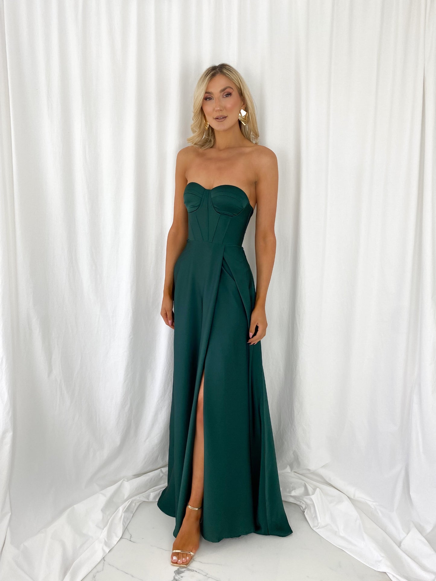a woman in a green dress standing in front of a curtain