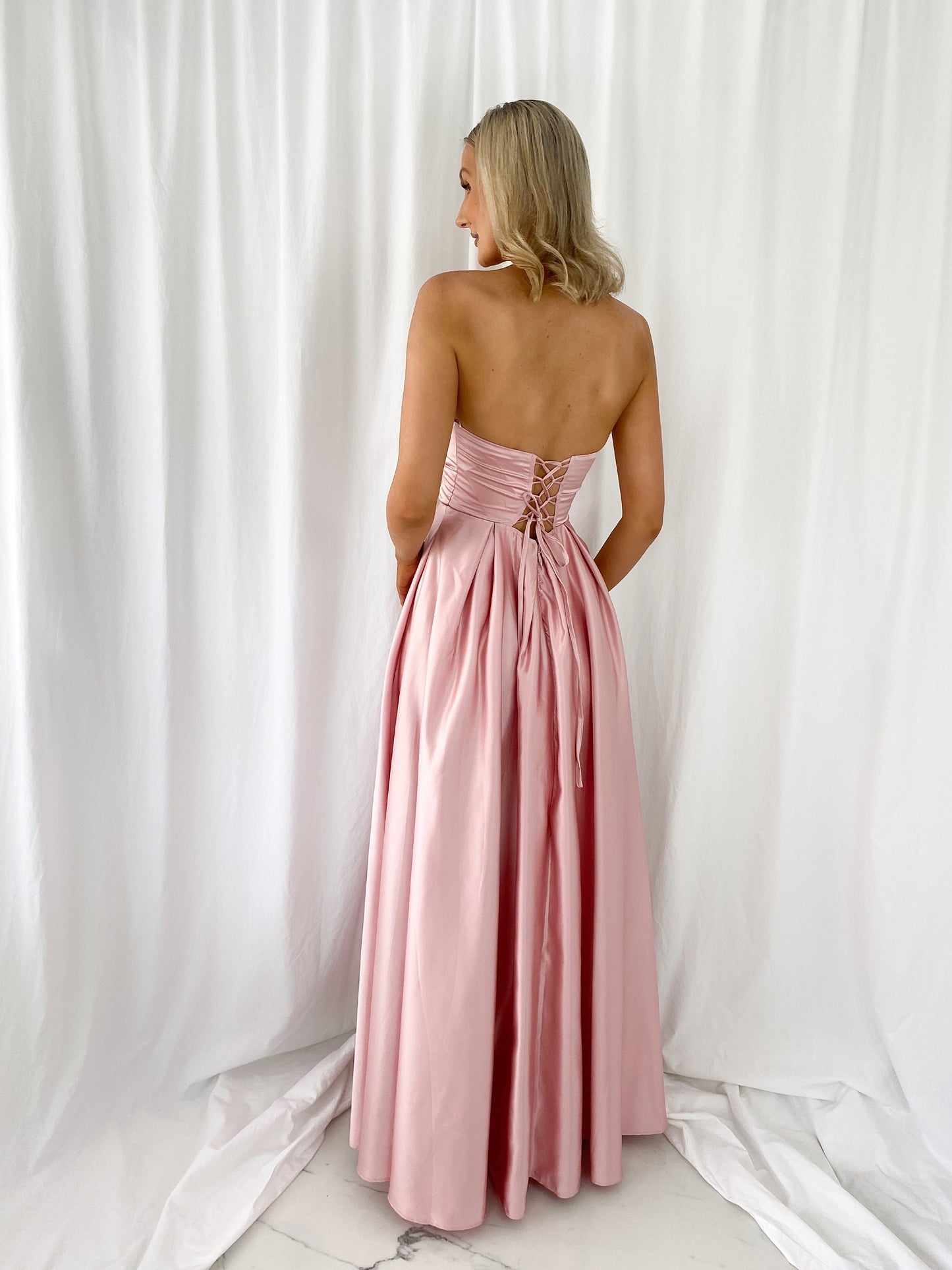a woman in a pink dress standing in a white dress