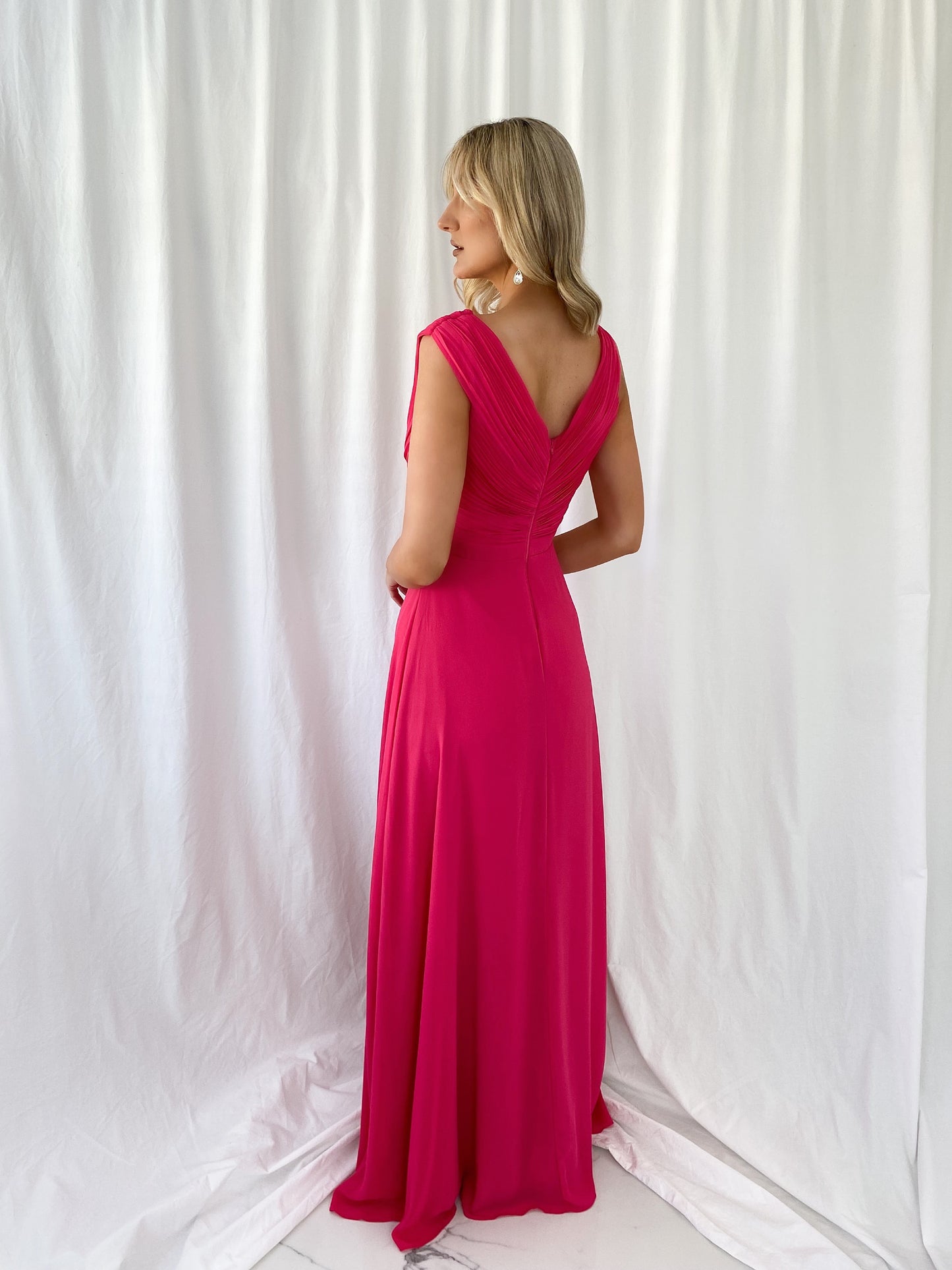 a woman in a pink dress talking on a cell phone