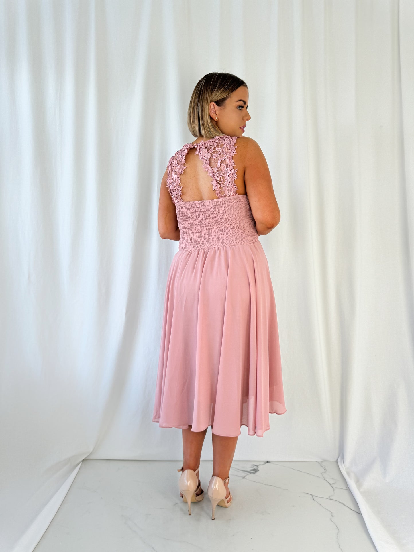 a woman in a pink dress standing in a white dress 