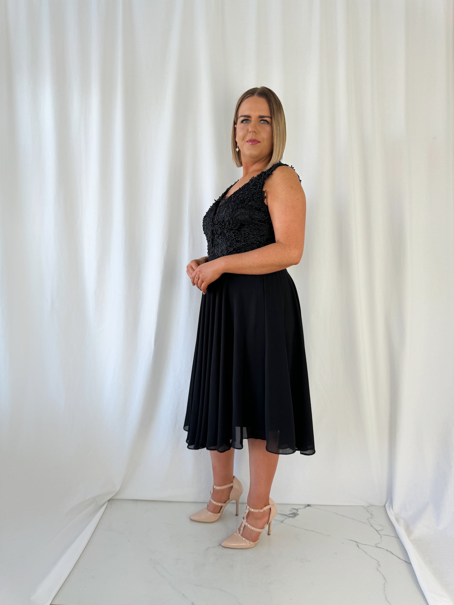 a woman in a dress standing in front of a curtain 