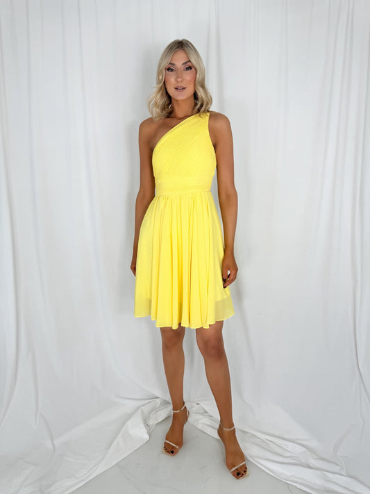 a woman in a yellow dress standing on a bed 