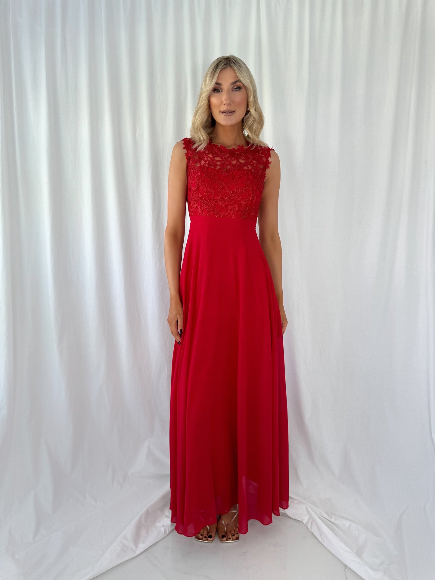 a woman in a red dress standing in front of a curtain 