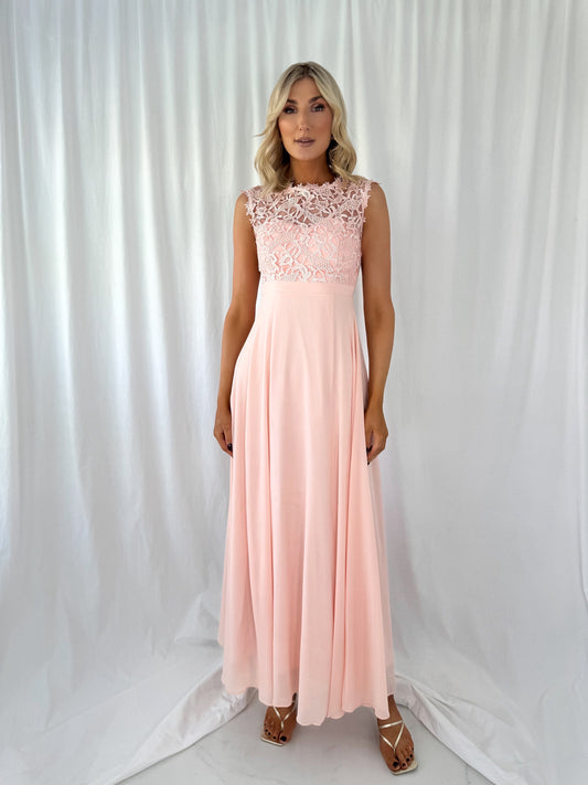 a woman in a pink dress standing in front of a curtain