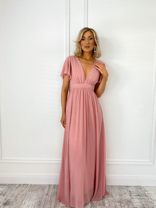 a woman in a pink dress standing in front of a door