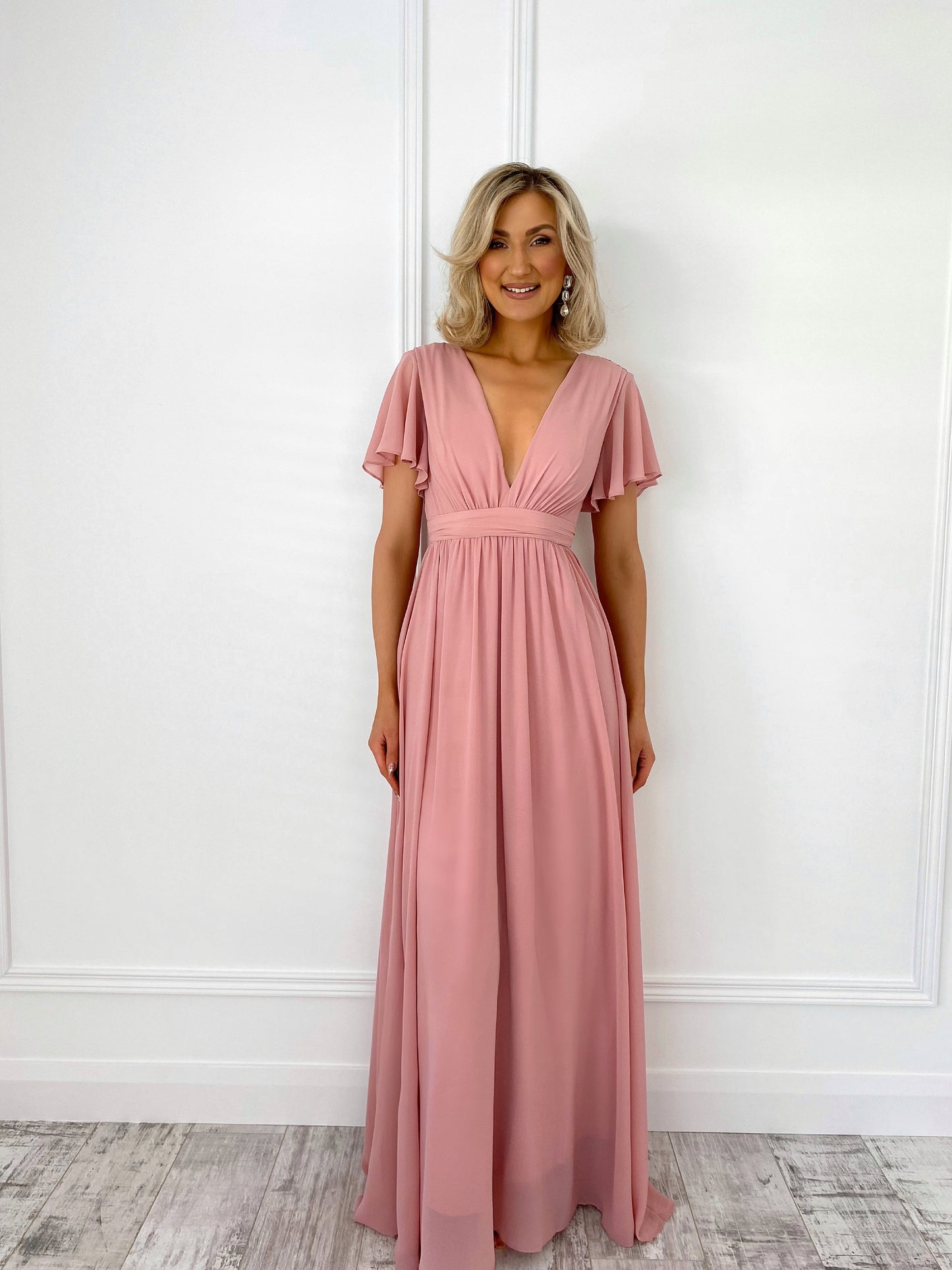 a woman in a pink dress standing in front of a door