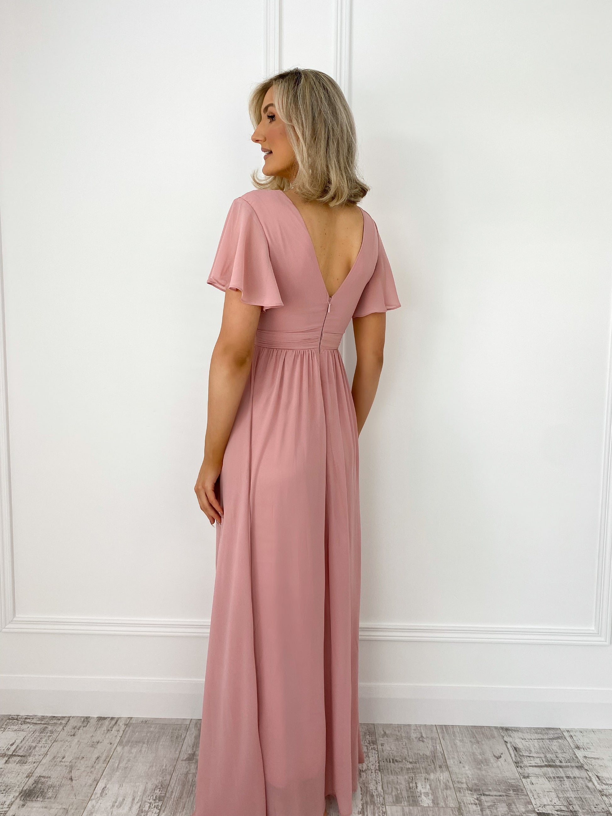 a woman in a pink dress standing in front of a door