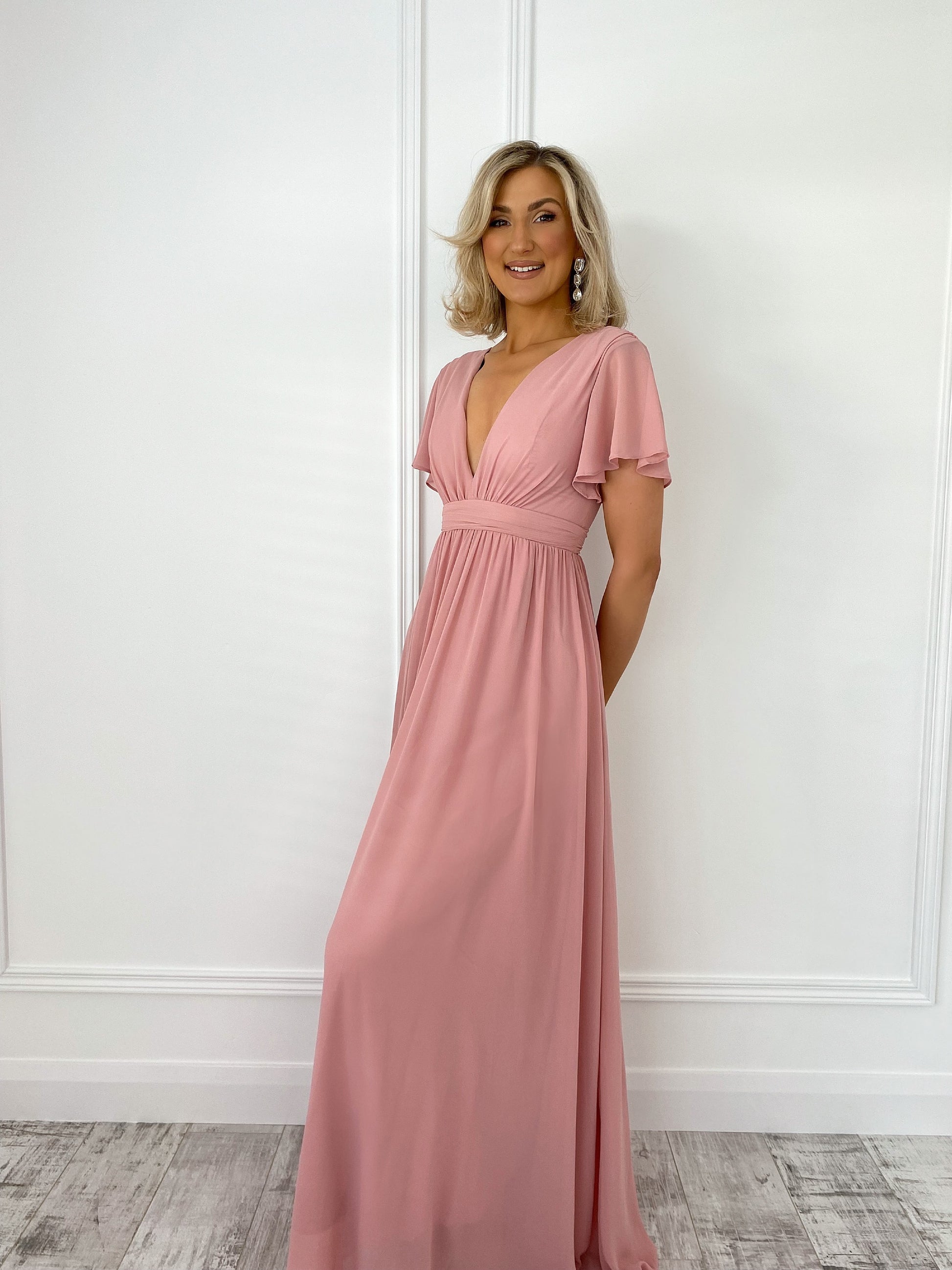 a woman in a pink dress standing in front of a door