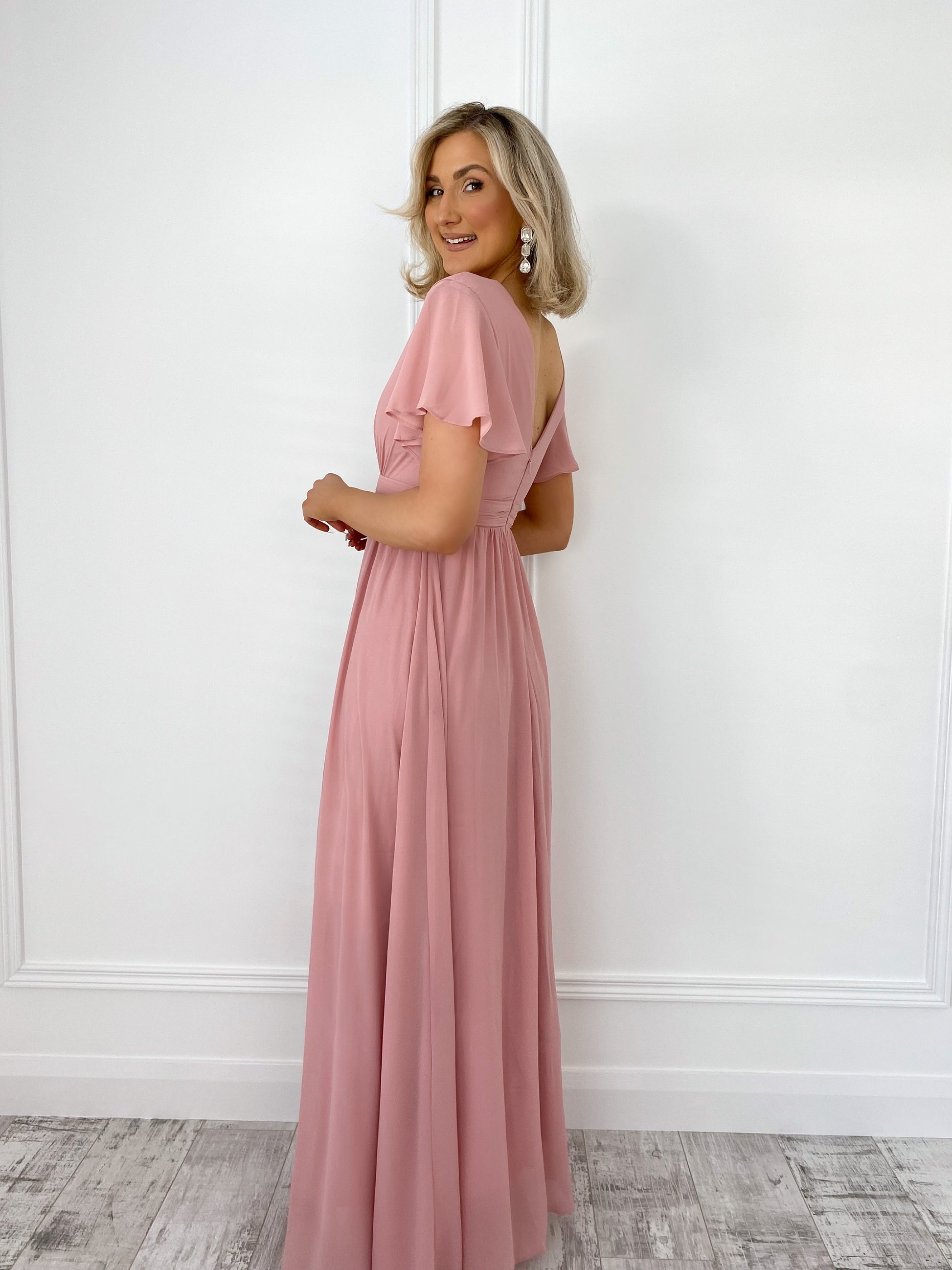 a woman in a pink dress standing in front of a door
