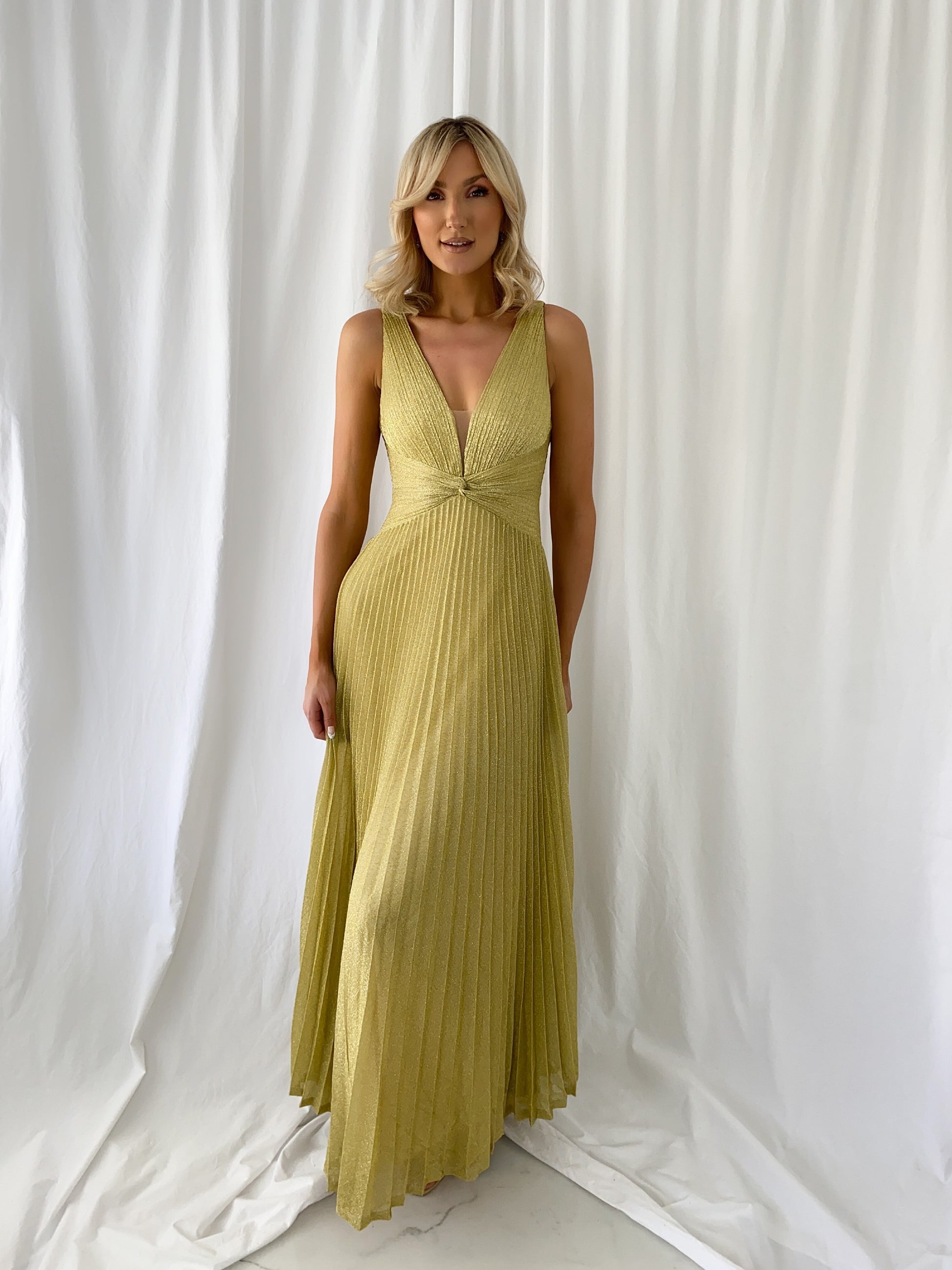 a woman in a yellow dress standing in front of a curtain 