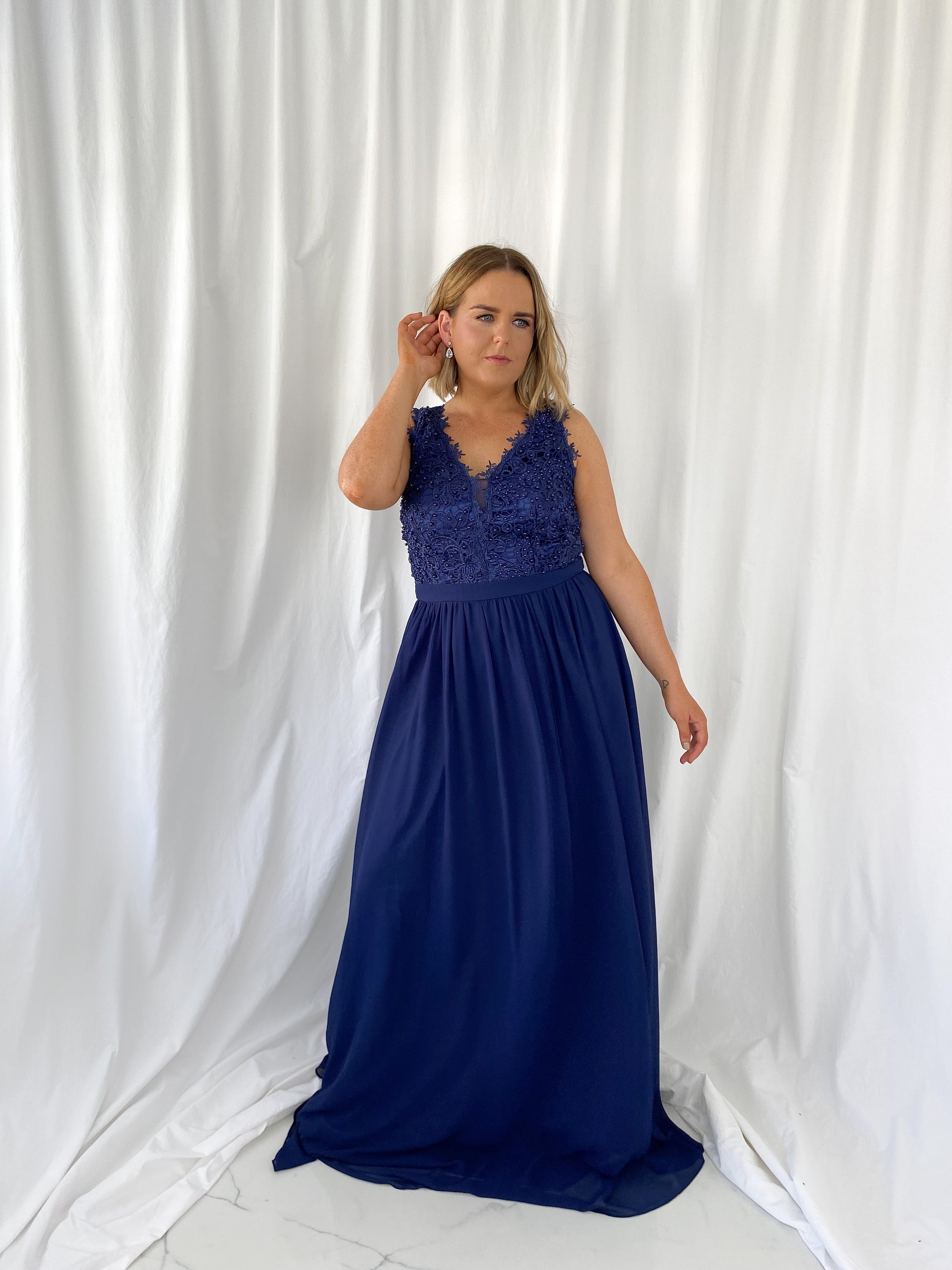 a woman in a blue dress talking on a cell phone 