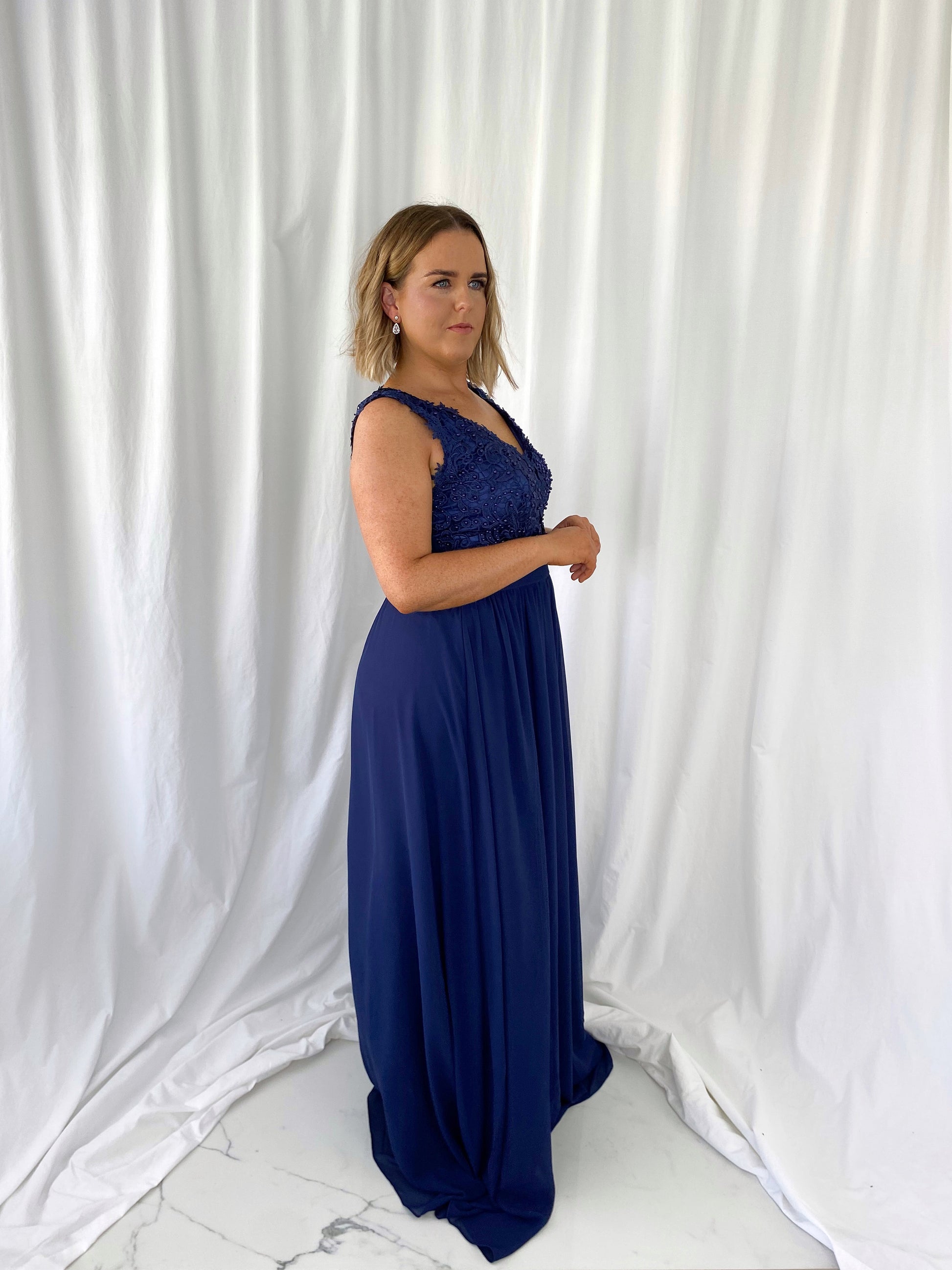 a woman in a blue dress talking on a cell phone 