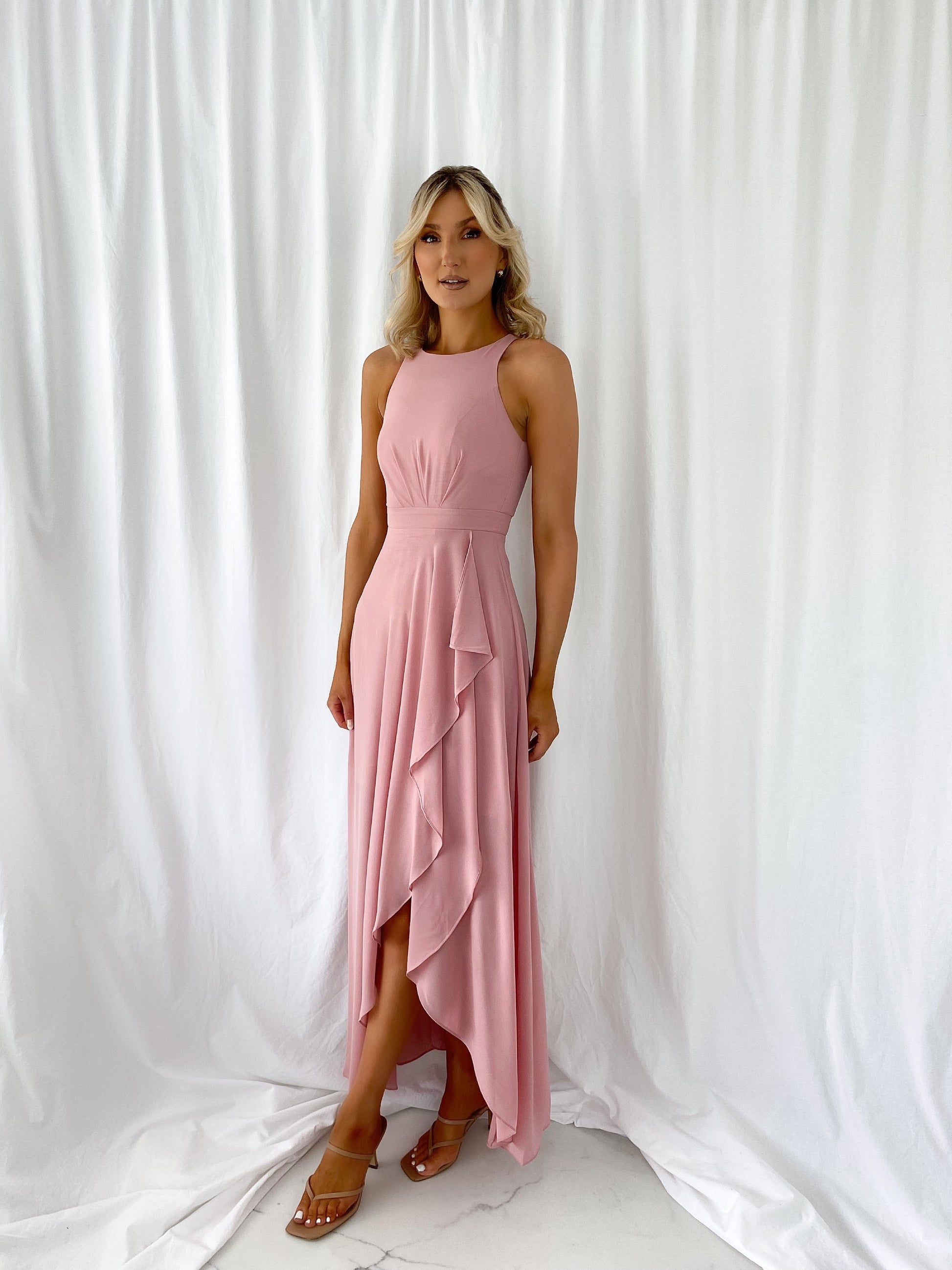 a woman in a pink dress standing on a bed 
