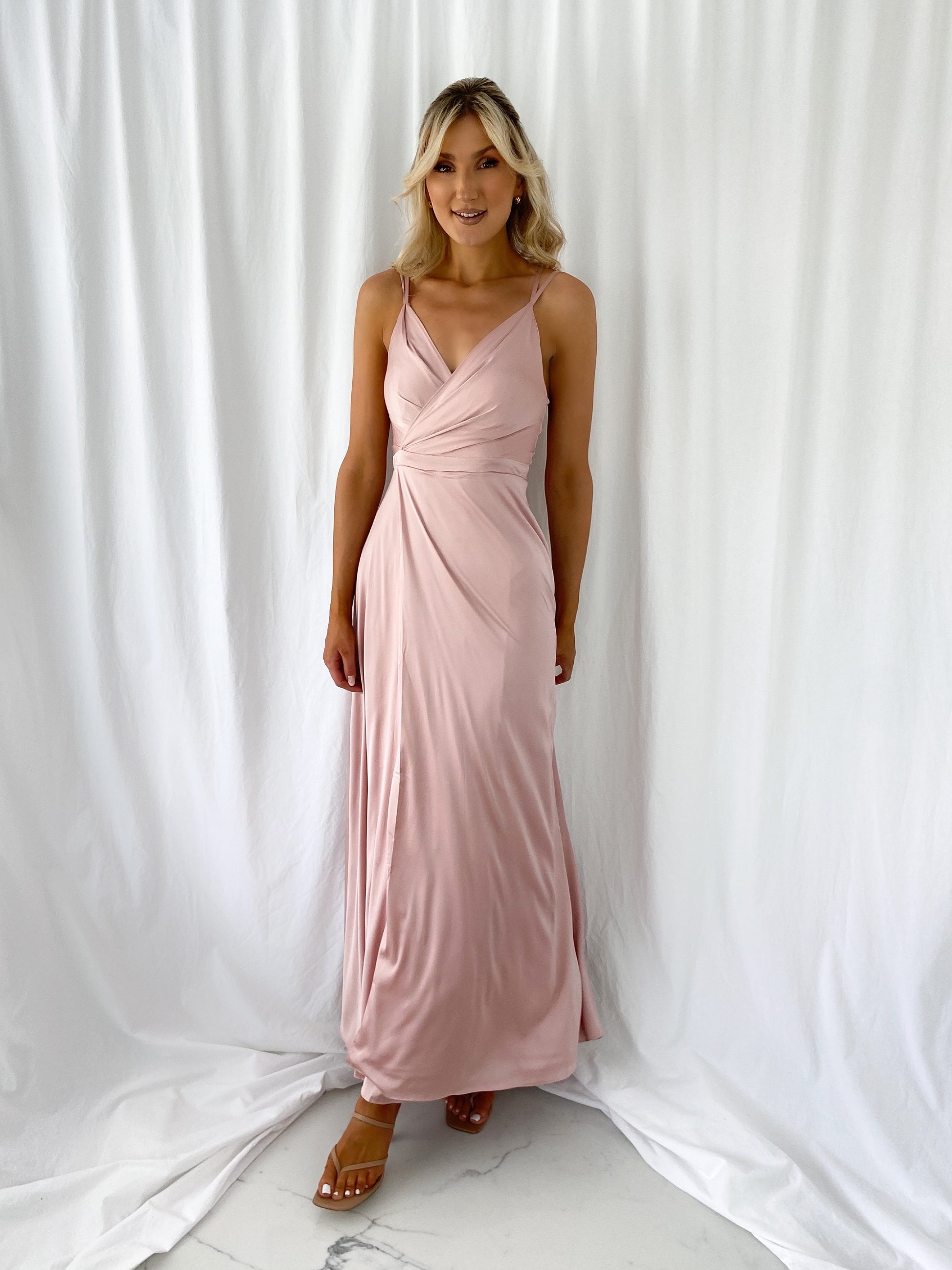 a woman in a pink dress standing in front of a curtain 