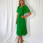 a woman in a green dress standing on a bed 