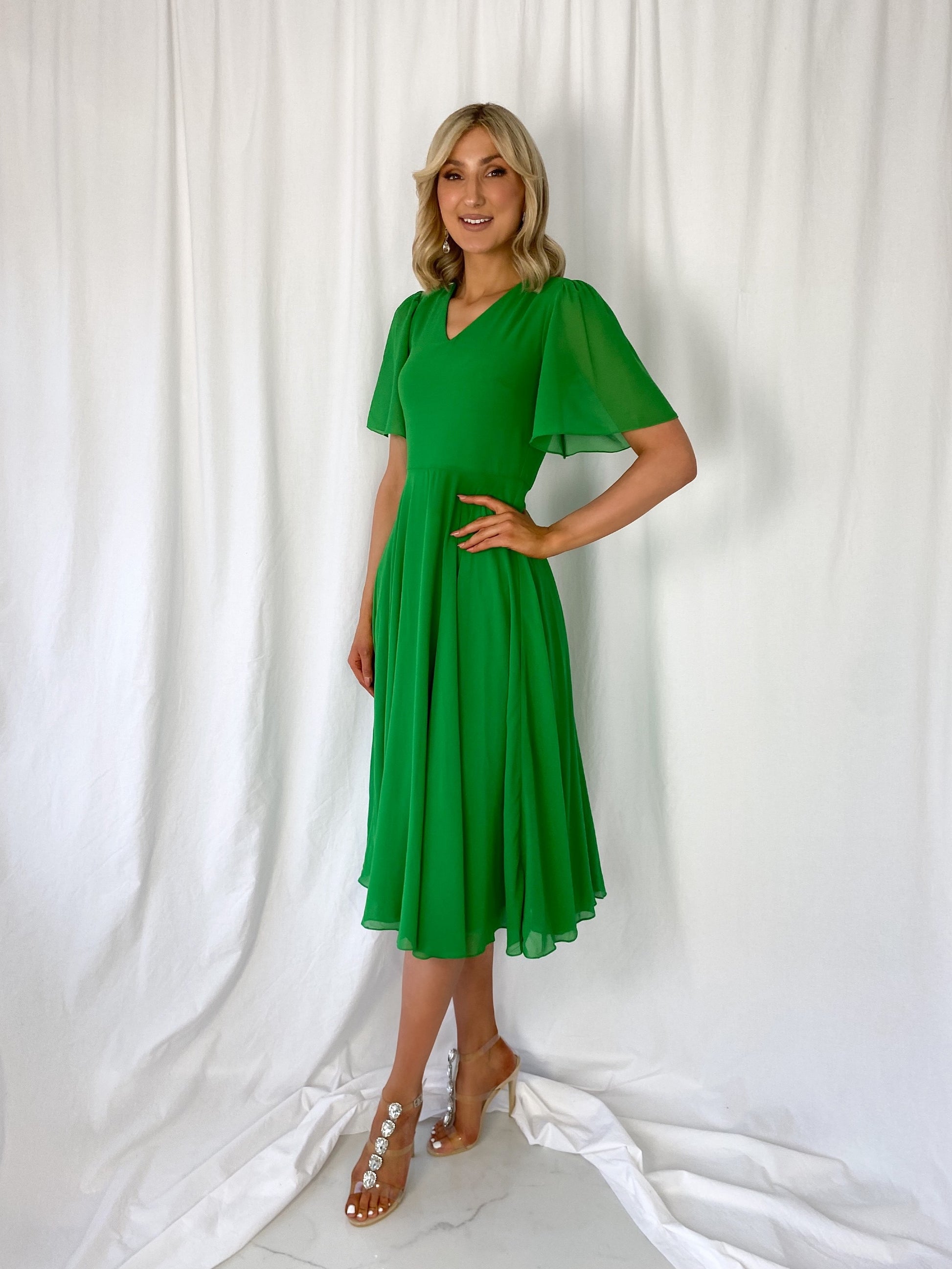 a woman in a green dress standing on a bed 