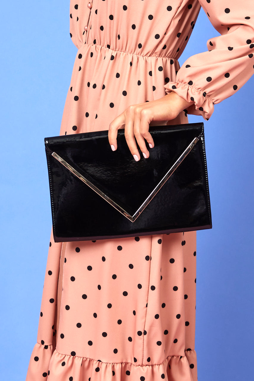 a woman in a black dress holding a black purse 